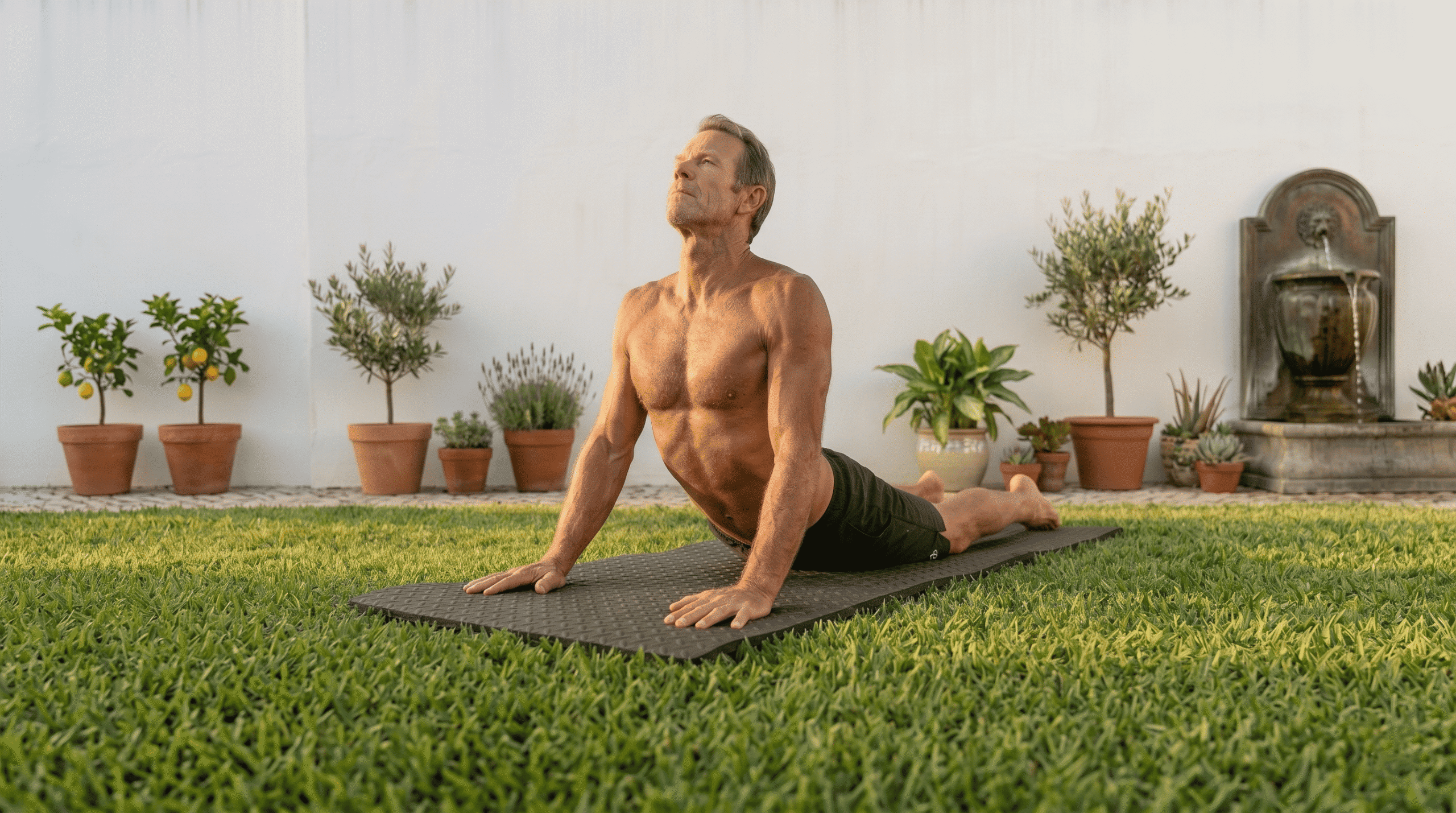 Yoga stretches for train for surfing: A surfer executing a deep lizard pose stretch on a yoga mat overlooking the ocean coastline.